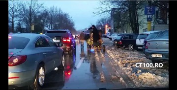 Un preot sfinţeşte cu agheasmă maşinile din trafic, dintr-o căruţă trasă de boi, cu Poliţia Locală Constanţa ca antemergător cu girofar