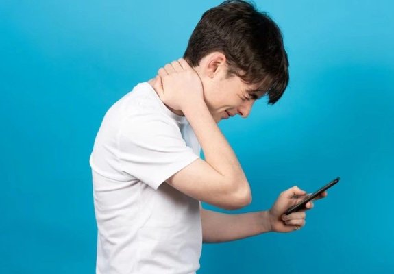 Stai cu capul aplecat spre telefon? Probabil suferi de sindromul „text neck“. Care sunt simptomele